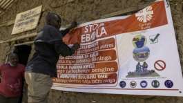 A man hangs an Ebola awareness banner in the Kigonze displaced persons camp in Bunia, in the eastern DRC.  By Glody MURHABAZI (AFP)