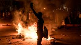 A demonstrator stands next to a burning barricade during a protest over The Gambias electricity crisis.  By Muhamadou BITTAYE (AFP)