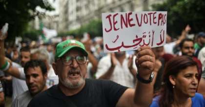 An Algerian protester holds a placard reading