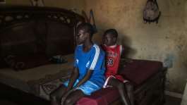 Fallou (L) and Bara (R), who lost their mother in 2024 when her pirogue capsized, watch TV at their home in Mbour, Senegal in March 2026.  By PATRICK MEINHARDT (AFP)
